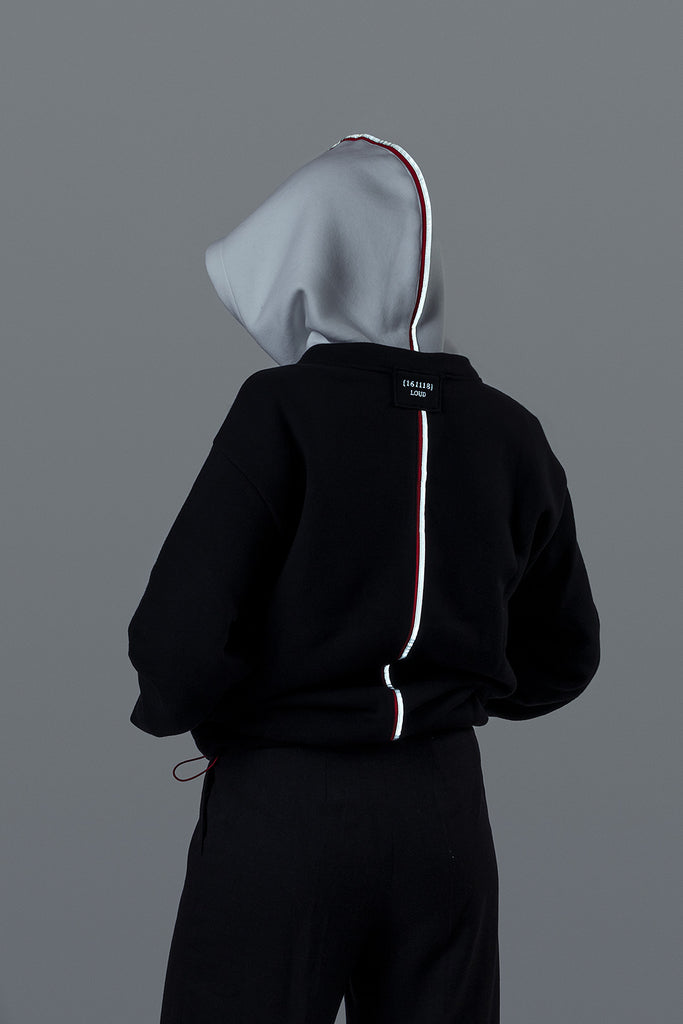 Designer hoodie and sweatshirt in black with white hood. Made of recycled PET bottles from the ocean and organic cotton. This hoodie has an exchangeable hood, adjustable length, reflective tape and embroidery. 